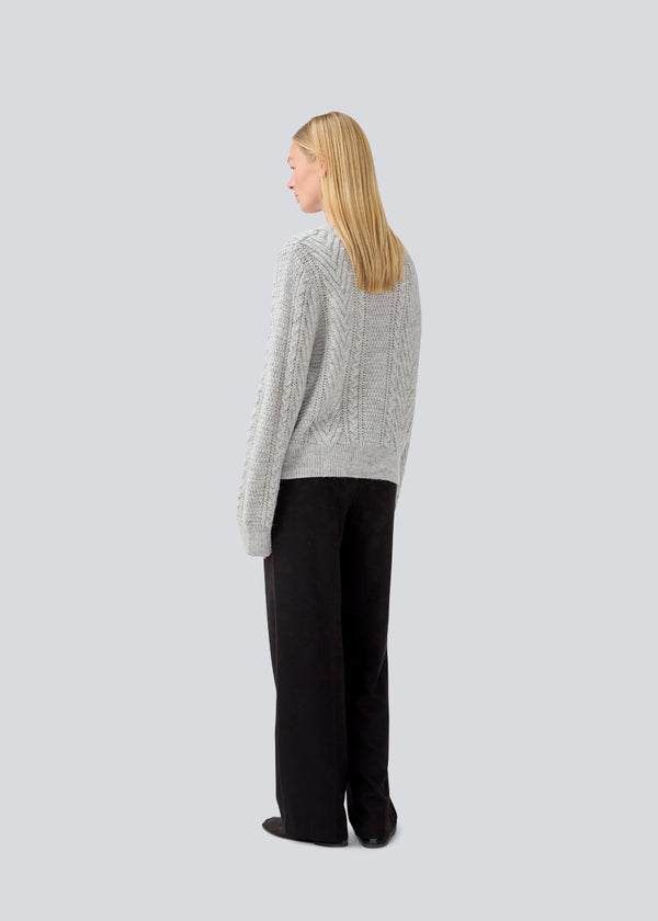 Grey cableknit jumper in wool-blend quality. GrannonMD o-neck has a relaxed fit with long sleeves and a round neck, with rib trimmings at neck, sleeves and hem. The model is 175 cm and wears a size S/36.