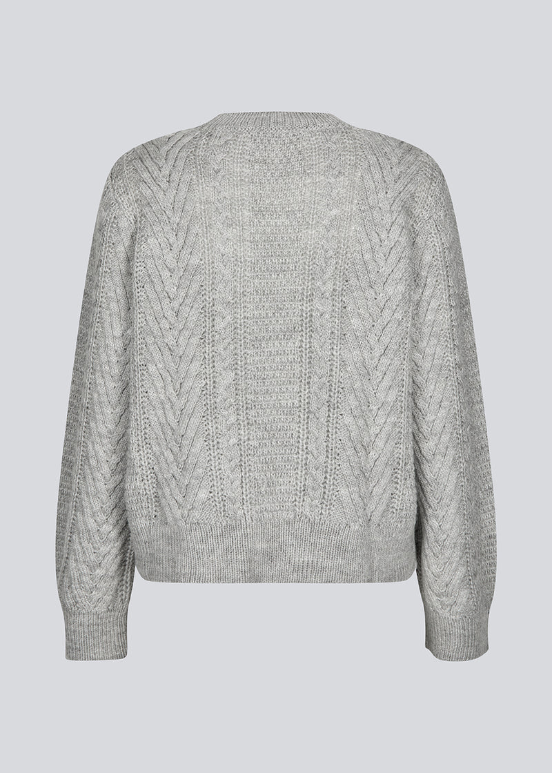 Grey cableknit jumper in wool-blend quality. GrannonMD o-neck has a relaxed fit with long sleeves and a round neck, with rib trimmings at neck, sleeves and hem. The model is 175 cm and wears a size S/36.