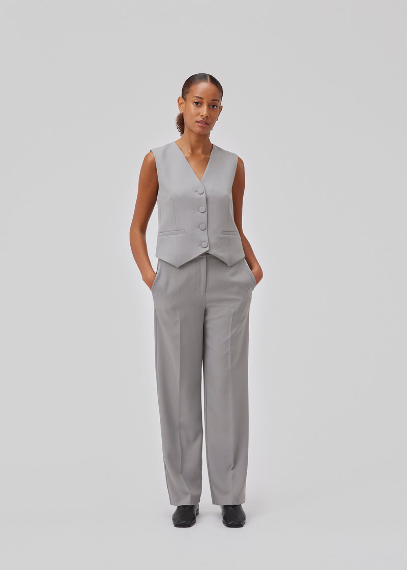 Tailored vest made from a recycled polyester blend. GrayMD vest is slightly cropped with a slim fit and paspoil front pockets, fabric covered buttons and pointed hems in front. The model is 175 cm and wears a size S/36.