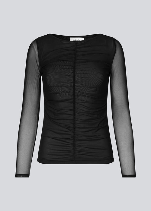 GwenMD top in black is a tight-fitted mesh top with gatherings in front. The top has a wide neckline and long sleeves, that are slightly more transparent than the body. The model is 175 cm and wears a size S/36.