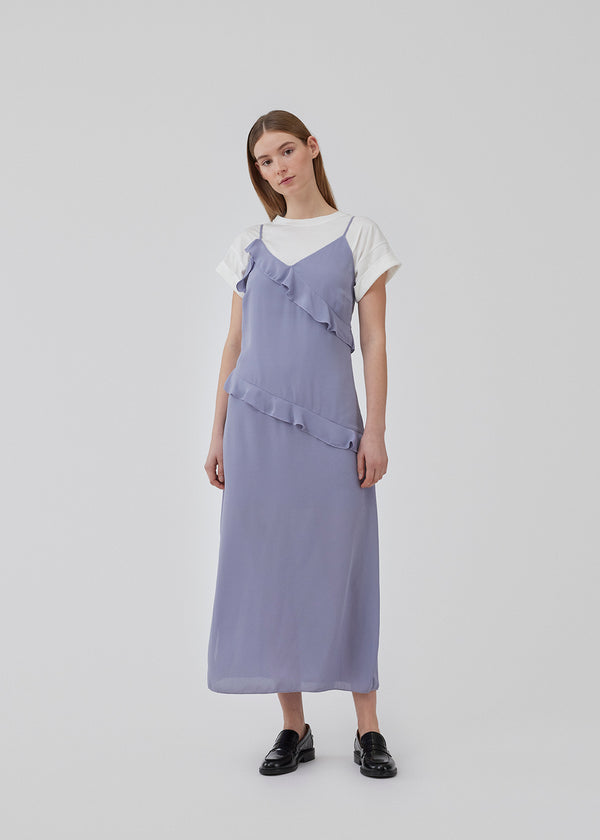 Midi dress in a recycled quality with an asymmetrical frilly detail, and slit at one side. HalimaMD dress has a v-neckline with small adjustable shoulderstraps. The model is 175 cm and wears a size S/36.