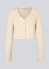 Cropped cardigan in beige made from a fluffy material. HamptonMD cardigan has long sleeves, v-shaped neckline, and is closed with two buttons in front. The model is 175 cm and wears a size S/36.