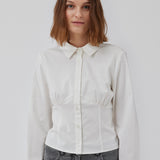 Form-fitting shirt in white in a woven cotton blend with collar, buttons in front, and long sleeves with cuff. HarrisonMD shirt has darts and a cutline below the chest for a corset-inspired look. The model is 175 cm and wears a size S/36.