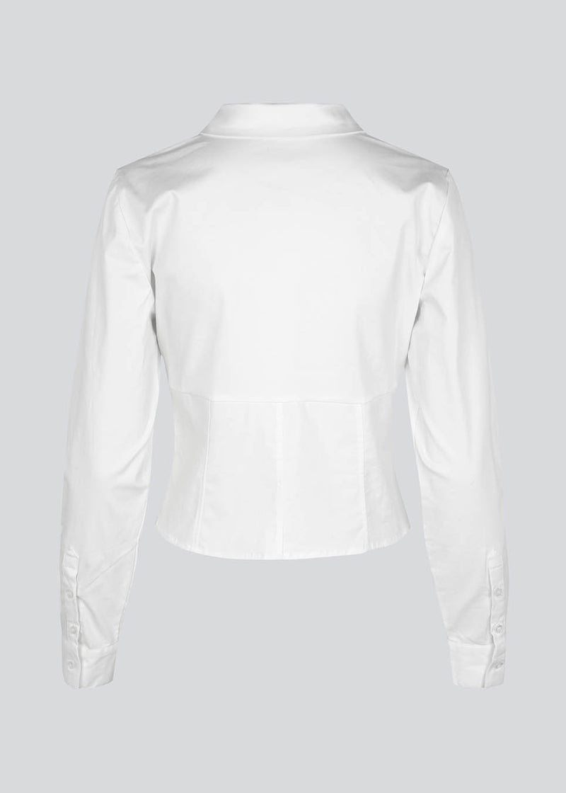Form-fitting shirt in white in a woven cotton blend with collar, buttons in front, and long sleeves with cuff. HarrisonMD shirt has darts and a cutline below the chest for a corset-inspired look. The model is 175 cm and wears a size S/36.