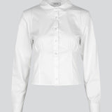 Form-fitting shirt in white in a woven cotton blend with collar, buttons in front, and long sleeves with cuff. HarrisonMD shirt has darts and a cutline below the chest for a corset-inspired look. The model is 175 cm and wears a size S/36.