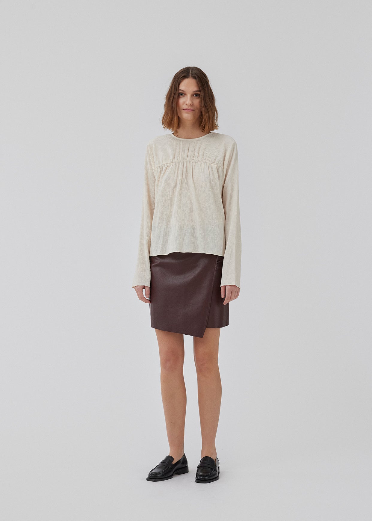 HiltonMD top in beige is designed with a relaxed fit, long sleeves and a round neckline with a hidden zipper at the back. The top is detailed with a ruching detail over the chest. The model is 175 cm and wears a size S/36.