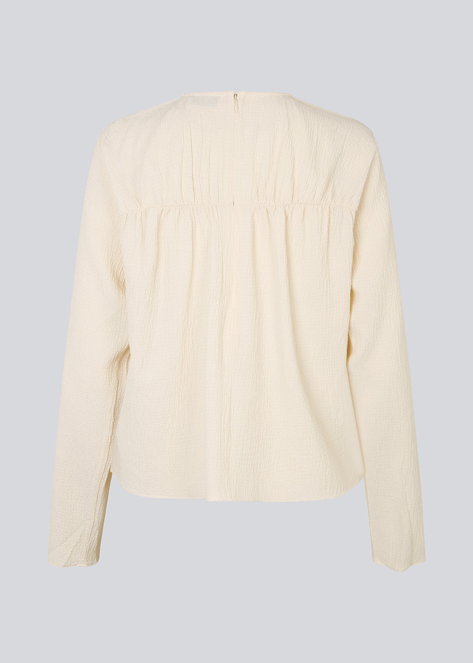 HiltonMD top in beige is designed with a relaxed fit, long sleeves and a round neckline with a hidden zipper at the back. The top is detailed with a ruching detail over the chest. The model is 175 cm and wears a size S/36.