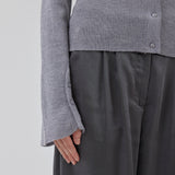 Fitted cardigan in grey melange made from a soft, rib-knitted wool. HirokiMD cardigan has a collar, buttons in front, and long sleeves with slit and buttons. The model is 175 cm and wears a size S/36.