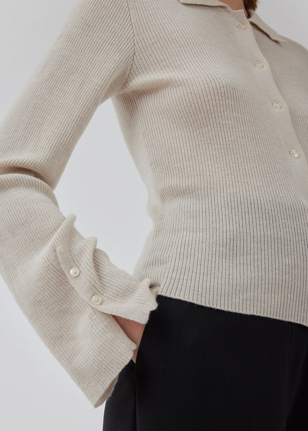 Fitted cardigan in beige made from a soft, rib-knitted wool. HirokiMD cardigan has a collar, buttons in front, and long sleeves with slit and buttons. The model is 175 cm and wears a size S/36.