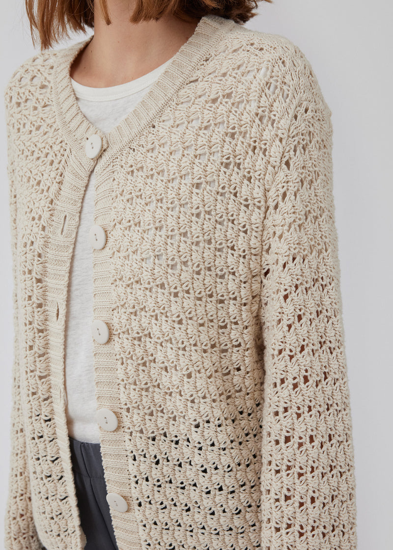 Cardigan in crochet look in organic cotton. HobbsMD solid cardigan has a casual look with a round neck with button closure in front, and long sleeves. The model is 175 cm and wears a size S/36.