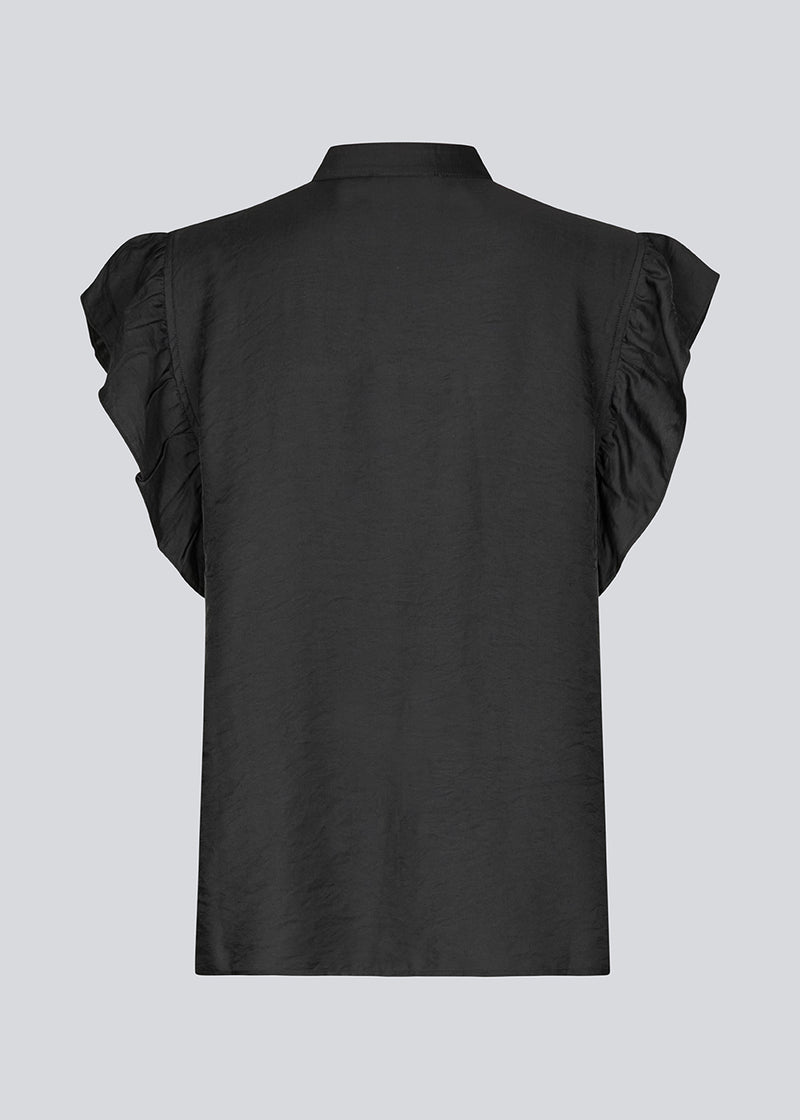 HolidayMD top in black is designed with a standing collar and button closure in front. The top has a frilly detail along the placket and at the armholes.&nbsp;