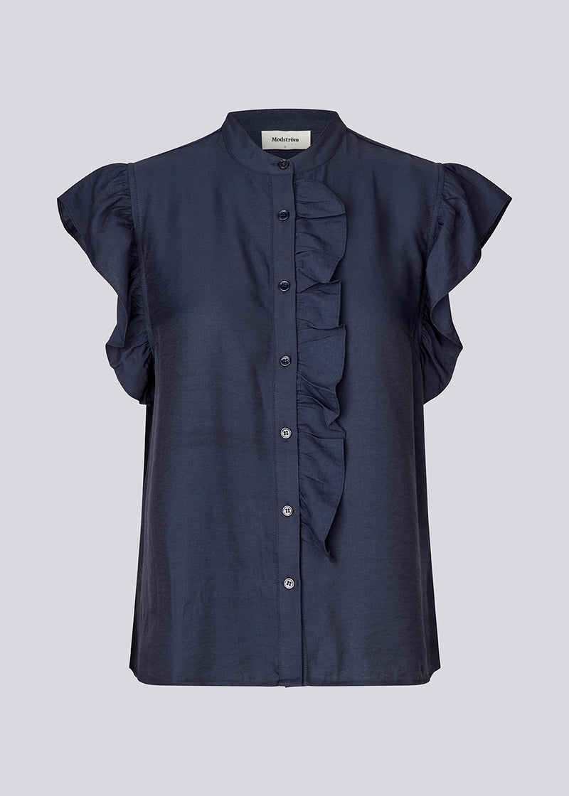 HolidayMD top in navy blue is designed with a standing collar and button closure in front. The top has a frilly detail along the placket and at the armholes.&nbsp;