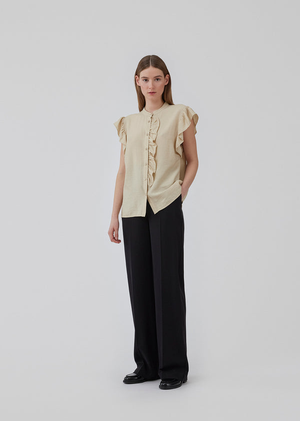 HolidayMD top in bright beige is designed with a standing collar and button closure in front. The top has a frilly detail along the placket and at the armholes. The model is 175 cm and wears a size S/36.