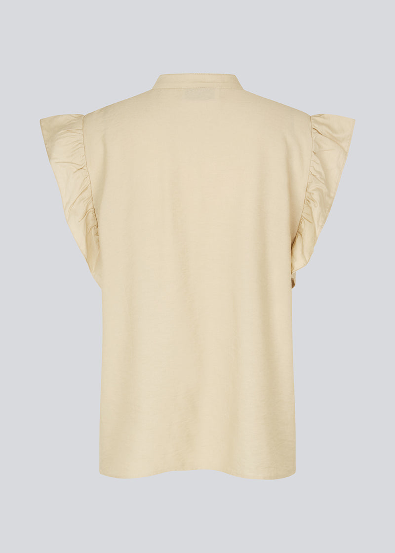 HolidayMD top in bright beige is designed with a standing collar and button closure in front. The top has a frilly detail along the placket and at the armholes. The model is 175 cm and wears a size S/36.