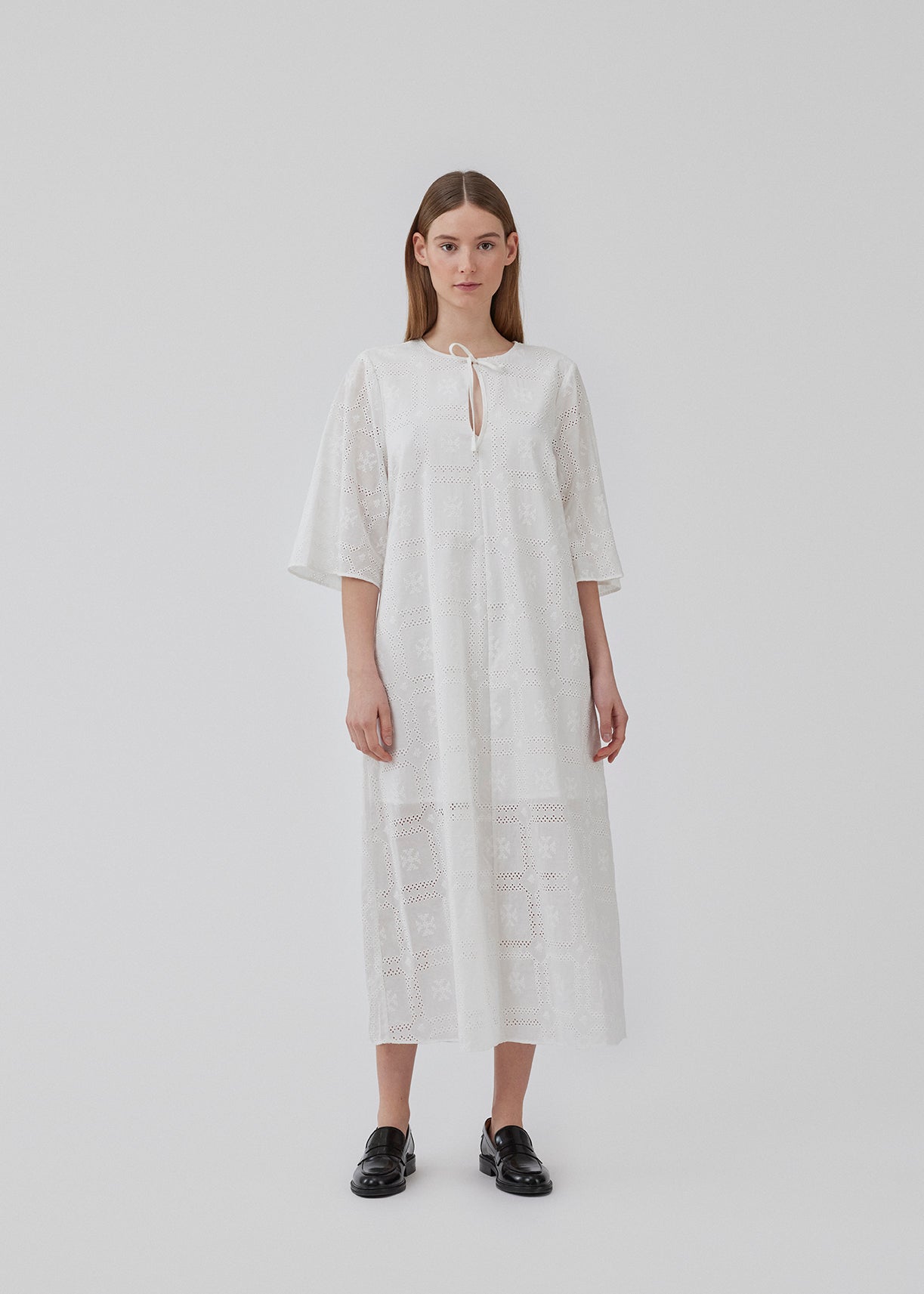 Broderie anglaise cotton dress in white with a casual fit and wide sleeves cutting at the elbow, and a opening in front with a tieband. HollynMD dress is lined. The model is 175 cm and wears a size S/36.