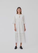 Broderie anglaise cotton dress in white with a casual fit and wide sleeves cutting at the elbow, and a opening in front with a tieband. HollynMD dress is lined. The model is 175 cm and wears a size S/36.