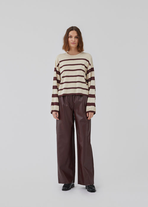 Relaxed knit jumper in beige  and burgundy in a quality made from a fine-knit linen. HurleyMD stripe o-neck has a round neck, slightly cropped length, and long wide sleeves with dropped shoulders. The model is 175 cm and wears a size S/36.