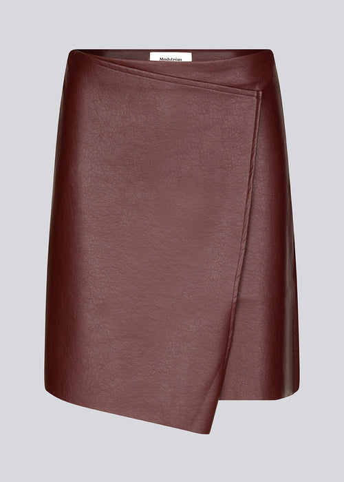 Short, asymmetrical wrap skirt in Burgundy in faux leather. HuxleyMD skirt has a hidden zipper closure at one side. The model is 175 cm and wears a size S/36.