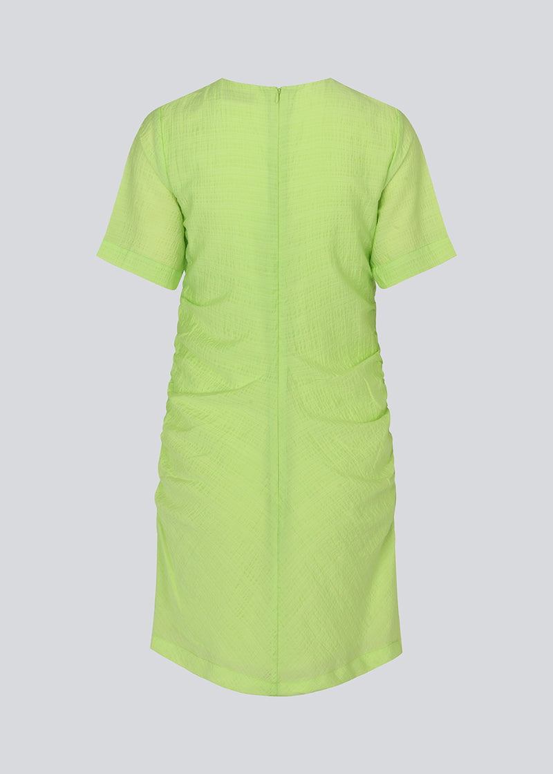 Fitted mini dress in green with an elastic gathering on the side. IbiMD dress has an invisible zipper in the back.