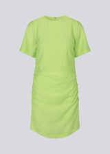 Fitted mini dress in green with an elastic gathering on the side. IbiMD dress has an invisible zipper in the back.