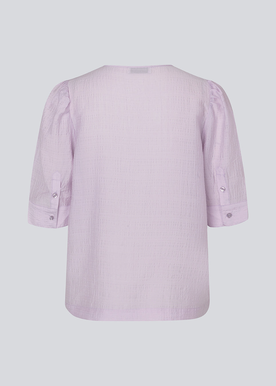 Loose top in light purple with short puff sleeves with a button closing. IbiMD top has an opening in the front with a tieband.