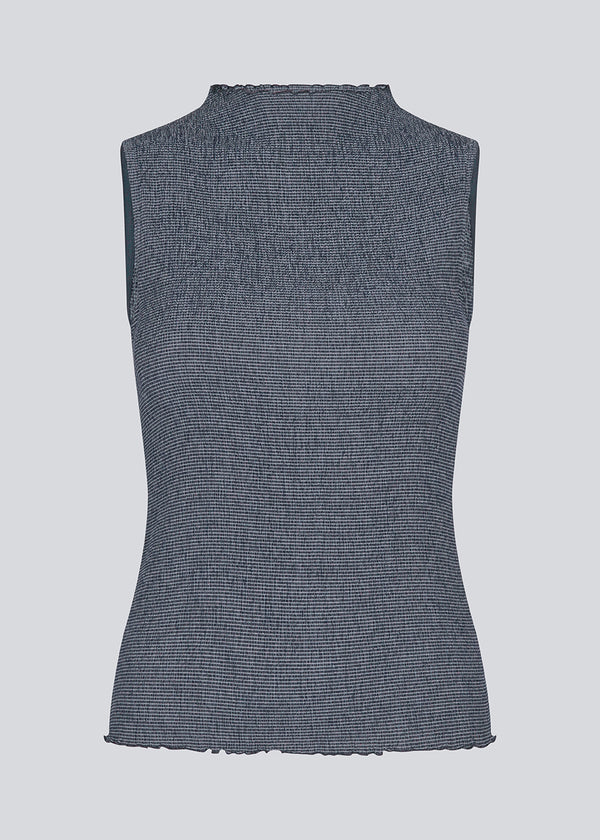 Sleeveless top in an elastic smock materiale. IbsenMD top is fitted, has a high neck and lettuce hems.