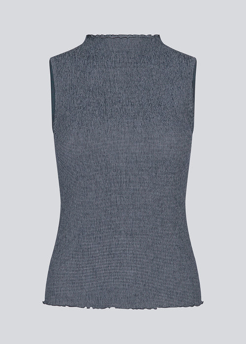 Sleeveless top in an elastic smock materiale. IbsenMD top is fitted, has a high neck and lettuce hems.