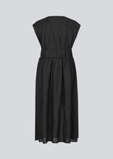 Sleeveless black maxi dress with a loose fit. IndiaMD dress has a deep v-neckline and a tie band at the waist and under the chest. The model is 177 cm and wears a size S/36.