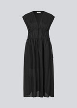 Sleeveless black maxi dress with a loose fit. IndiaMD dress has a deep v-neckline and a tie band at the waist and under the chest. The model is 177 cm and wears a size S/36.