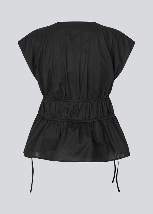 Sleeveless black top in a loose fit. IndiaMD top has a deep v-neckline and tie bands at the waist and under the chest.