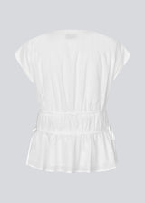 Sleeveless top in white in a loose fit. IndiaMD top has a deep v-neckline and tie bands at the waist and under the chest.