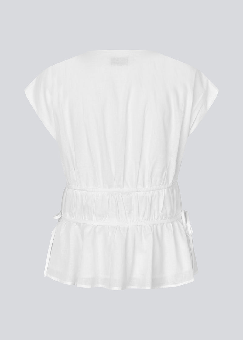 Sleeveless top in white in a loose fit. IndiaMD top has a deep v-neckline and tie bands at the waist and under the chest.