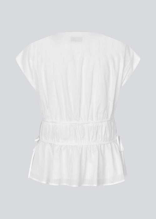 Sleeveless top in white in a loose fit. IndiaMD top has a deep v-neckline and tie bands at the waist and under the chest.