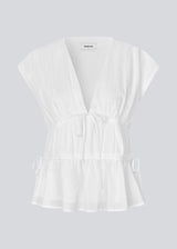 Sleeveless top in white in a loose fit. IndiaMD top has a deep v-neckline and tie bands at the waist and under the chest.