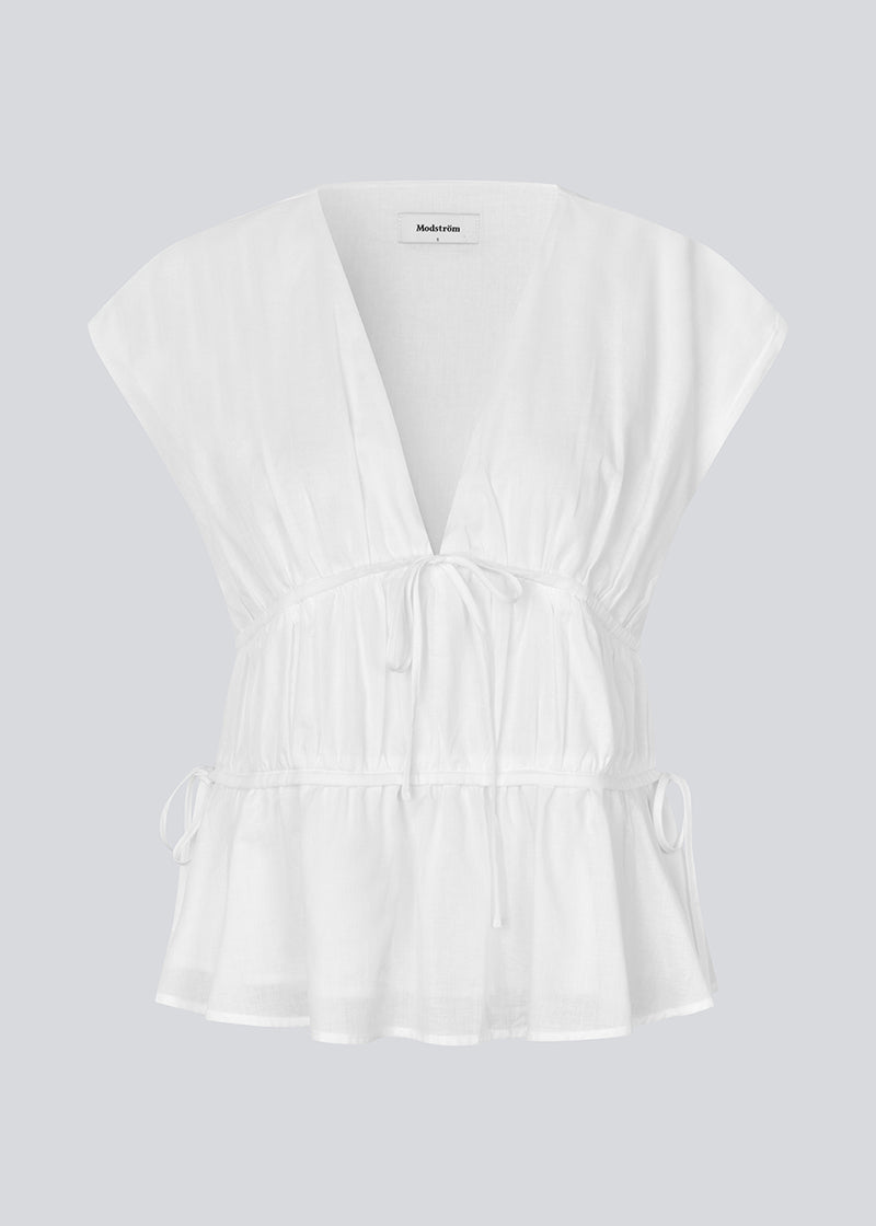 Sleeveless top in white in a loose fit. IndiaMD top has a deep v-neckline and tie bands at the waist and under the chest.