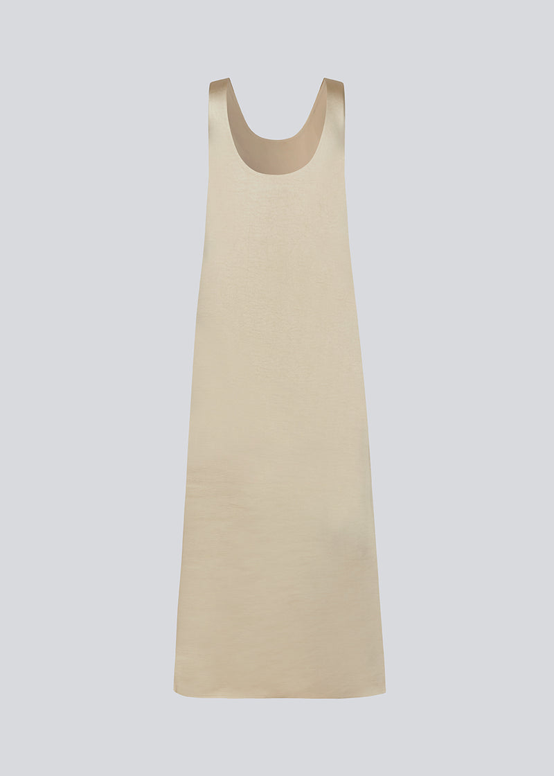 Long dress in beige in satin with an A-line silhouette. IolaMD dress has a deep back neckline and wide straps. The model is 177 cm and wears a size S/36.