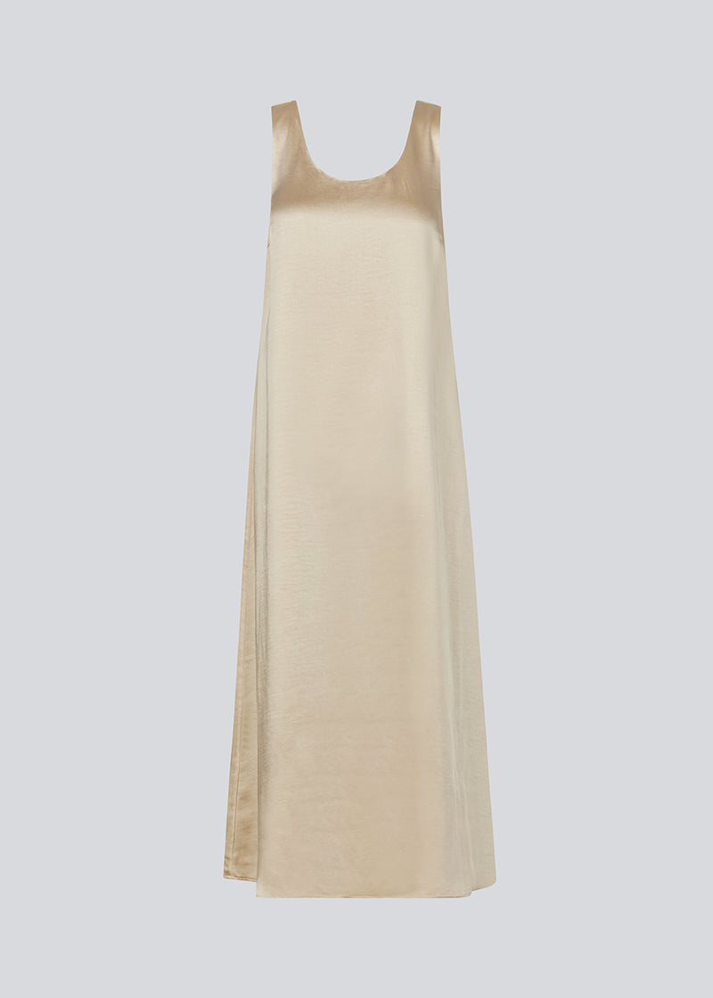 Long dress in beige in satin with an A-line silhouette. IolaMD dress has a deep back neckline and wide straps. The model is 177 cm and wears a size S/36.