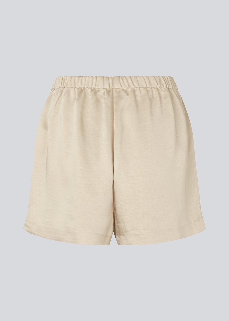 Lose beige shorts in satin with an elastic waist. IolaMD shorts has a medium high waist and side pockets. The model is 177 cm and wears a size S/36.