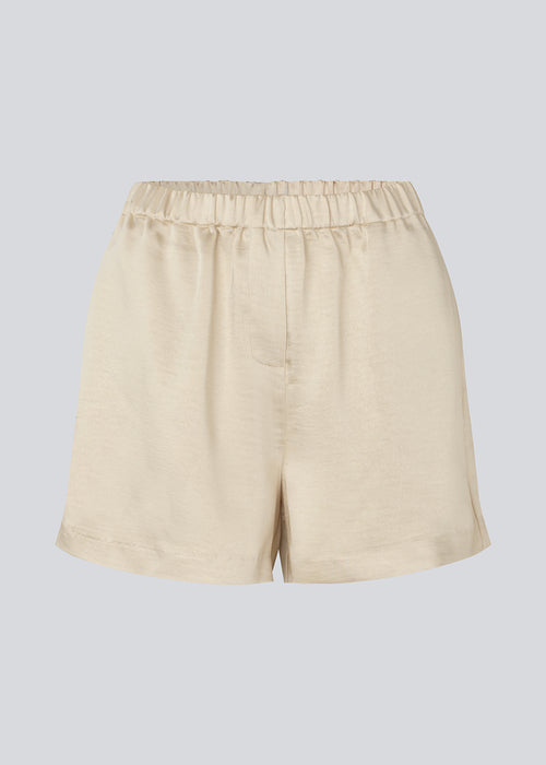 Lose beige shorts in satin with an elastic waist. IolaMD shorts has a medium high waist and side pockets. The model is 177 cm and wears a size S/36.