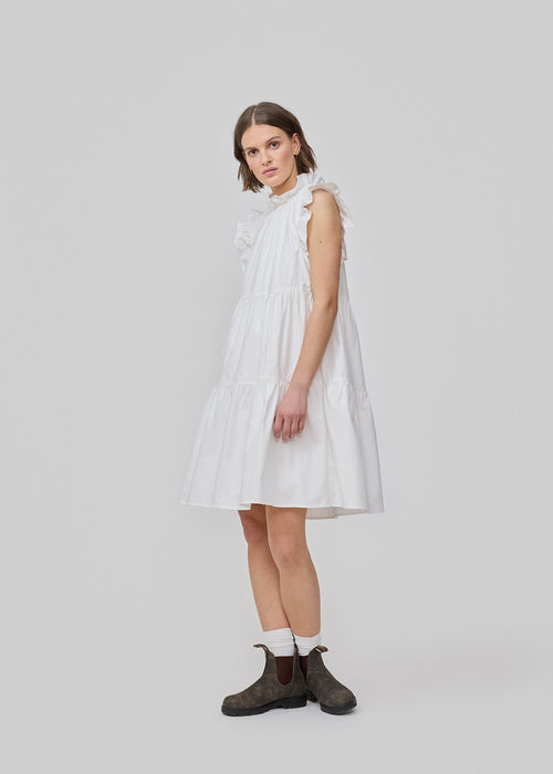 Sleeveless white dress in casual fit. The IZakMD dress has a ruffle detail at the sleeve and neck and is closed with a hidden zipper in the back. The model is 177 cm and wears a size S/36.