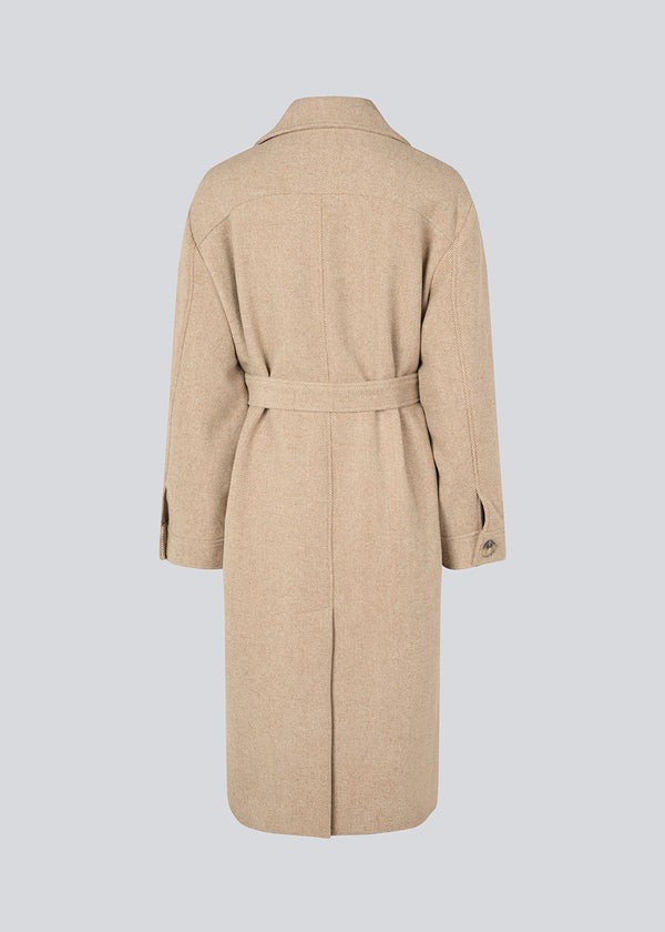 Long beige coat in twill with a tieband. JakariMD coat has wide revers, buttonclosure and a slit in the back.