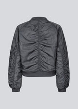 Classic bomber jacket in a grey color with gathering details. JeromoMD bomber jacket has padding, a pocket at the sleeve and a zipper closure. The model is 175 cm and wears a size S/36.