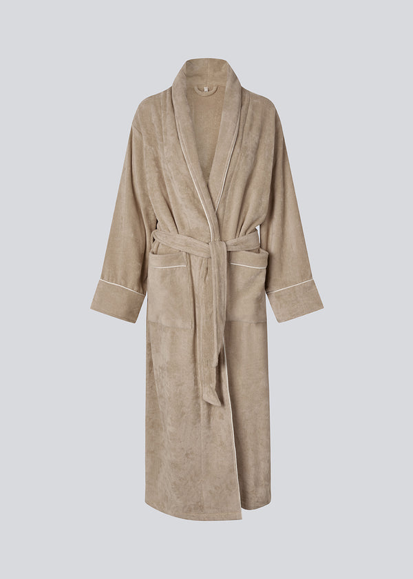 Beige oversized bathrobe. Josefinemd bathrobe is made from 100% organic cotton. It features large pockets, a belt, and contrast trims for an elegant touch. Finished with a subtle logo on the back – ideal for cozy mornings.&nbsp; Josefine Vogt (165 cm) and the model (177 cm) are both wearing size Small.