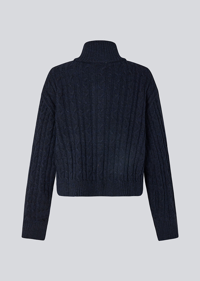 Josefine Vogt – high-neck cardigan. The Josefinemd knit cardigan features a cable-knit design with a high collar, buttoned cuffs, and front pockets. Timeless and perfect for chilly days, or as a layering piece over dresses and tops.