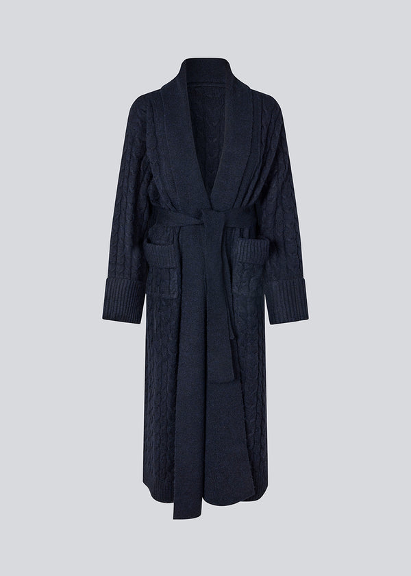 Blue cable-knit long cardigan. The Josefinemd robe is a long cardigan featuring pockets and a tie belt. Perfect for cozy mornings and chilly winter days.&nbsp;Josefine Vogt (165 cm) and the model (177 cm) are both wearing size Small.