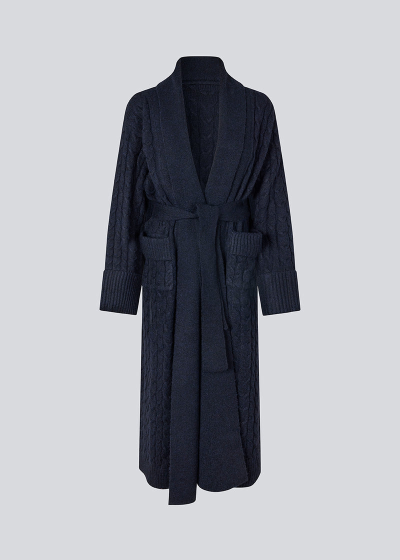 Blue cable-knit long cardigan. The Josefinemd robe is a long cardigan featuring pockets and a tie belt. Perfect for cozy mornings and chilly winter days.&nbsp;Josefine Vogt (165 cm) and the model (177 cm) are both wearing size Small.