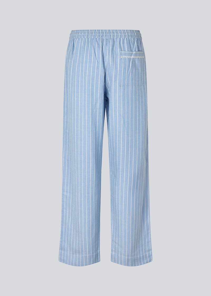 Blue classic striped pyjamas. The pyjamas is sold as a set of shirt and pants in the same size. Josefinemd pyjamas are made from 100% soft cotton and feature a classic fit with a collar, button closure, and drawstring trousers. Finished with delicate wave trim and comes with a matching pouch with logo. Josefine Vogt (165 cm) and the model (177 cm) are both wearing size Small.