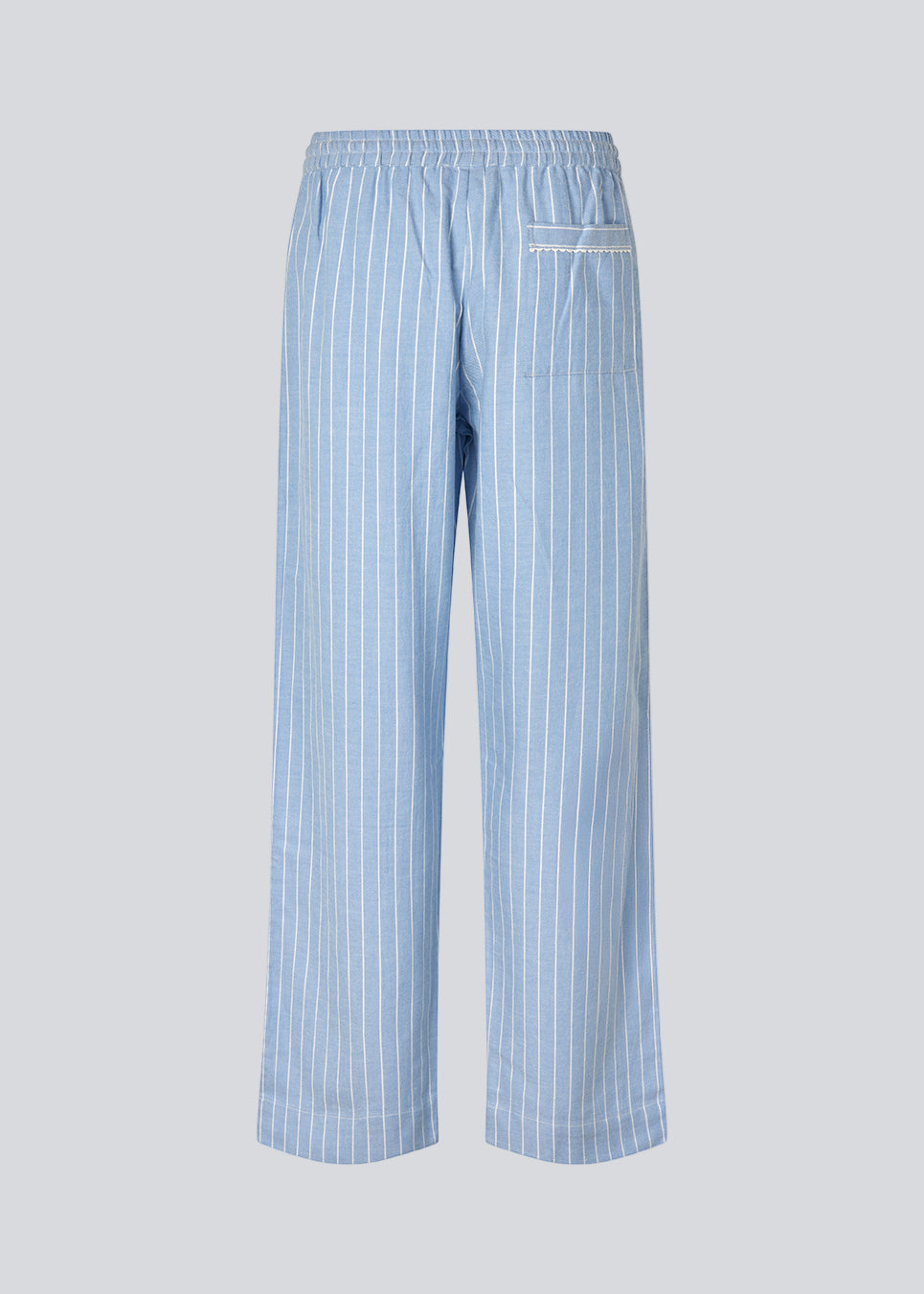 Blue classic striped pyjamas. The pyjamas is sold as a set of shirt and pants in the same size. Josefinemd pyjamas are made from 100% soft cotton and feature a classic fit with a collar, button closure, and drawstring trousers. Finished with delicate wave trim and comes with a matching pouch with logo. Josefine Vogt (165 cm) and the model (177 cm) are both wearing size Small.