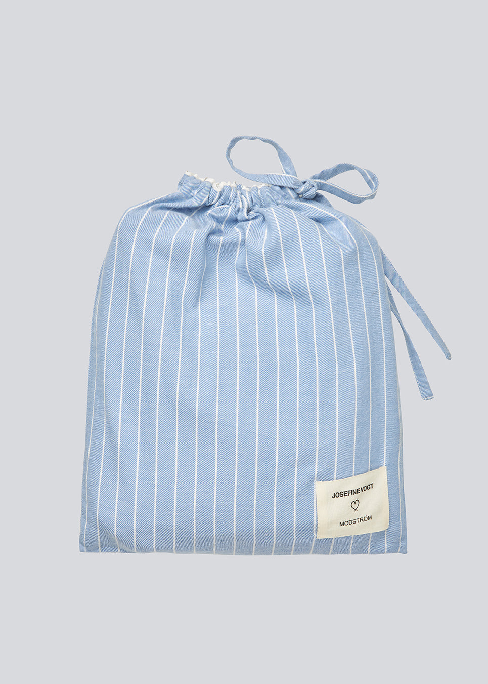 Blue classic striped pyjamas. The pyjamas is sold as a set of shirt and pants in the same size. Josefinemd pyjamas are made from 100% soft cotton and feature a classic fit with a collar, button closure, and drawstring trousers. Finished with delicate wave trim and comes with a matching pouch with logo. Josefine Vogt (165 cm) and the model (177 cm) are both wearing size Small.