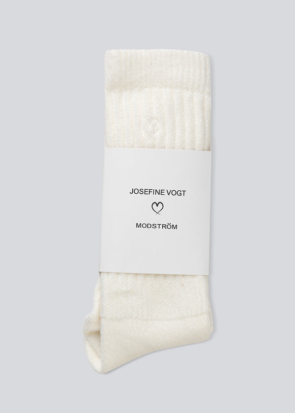 Modström x Josefine Vogt – White knitted Socks. Josefinemd socks are long, soft, and feature a subtle embroidered heart. Perfect for cozy moments at home or on the go.&nbsp;